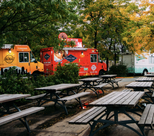 Drei Foodtrucks geparkt vor mehreren Bänken, Teil eines Veganen Caterings.