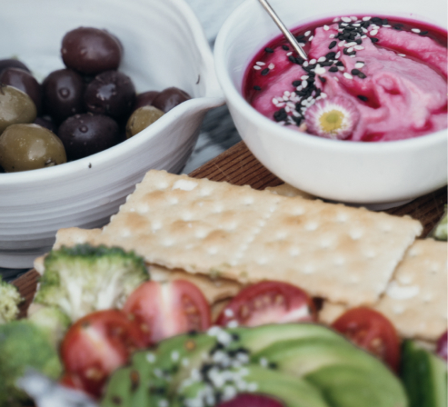 Eine Schüssel gefüllt mit Trauben und eine gefüllt mit Joghurt, angerichtet mit Brot und Salat als Teil eines veganen Caterings.