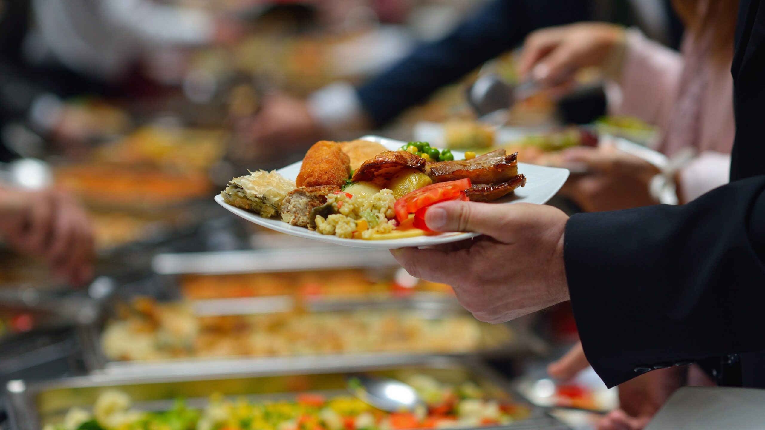 Employee standing at a team lunch buffet with a plate in hand. 