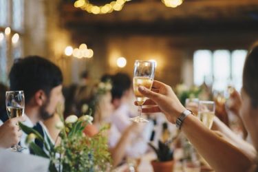 Mehrere Personen auf einer Business-Party in Berlin stoßen in der Luft an.